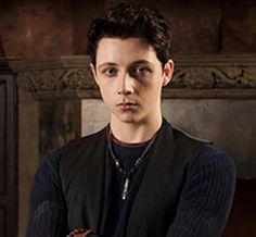 a young man is posing for a photo in front of a fireplace with his arms crossed