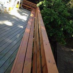 a wooden bench sitting on top of a wooden deck next to a lush green forest