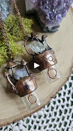 two small glass vases sitting on top of a wooden table next to rocks and moss