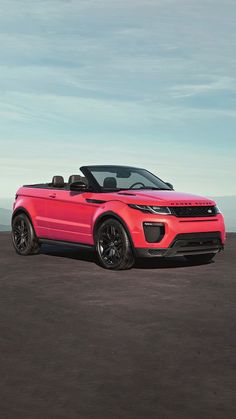 a red range rover convertible parked on the beach