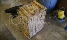 a wooden box sitting on the ground next to a trash can