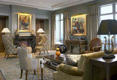 a living room filled with lots of furniture next to large window covered in drapes