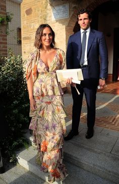 a man in a suit and tie standing next to a woman wearing a floral dress