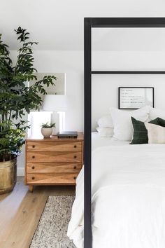 a bedroom with white bedding and green plants on the nightstands next to it