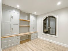 an empty room with white cabinets and wood floors