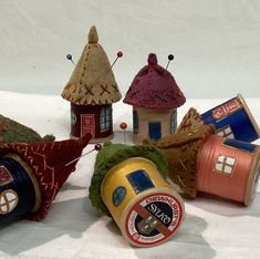 several small houses made out of yarn and thread on a white tablecloth covered surface