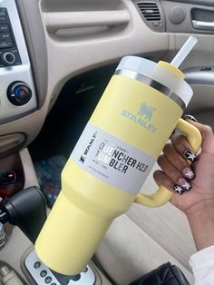 a person holding a yellow coffee cup in their hand while sitting in the driver's seat of a car