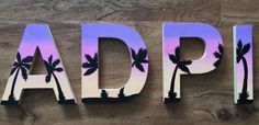 the letters are made out of wood and have palm trees painted on them in different colors