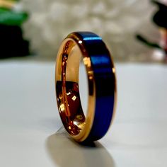 a gold and blue wedding ring sitting on top of a table