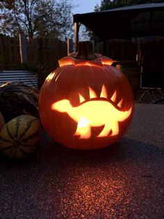 a carved pumpkin sitting on the ground next to other pumpkins