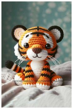 a small crocheted tiger sitting on top of a bed