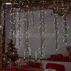 christmas lights hanging from the ceiling in front of a dining room table with presents on it