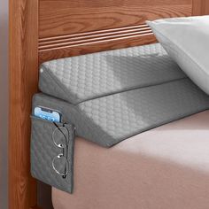 a close up of a bed with two pillows and an eyeglass holder on it