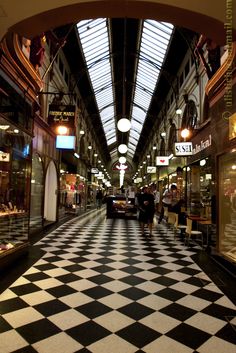 the inside of a shopping mall with checkered floor and skylights above it,