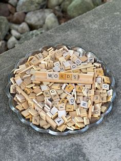 a bowl filled with wooden scrabbles sitting on top of a stone slab