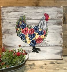 a painted rooster on a wooden wall next to flowers