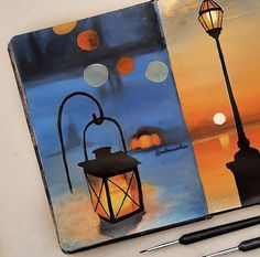 an open notebook with a painting of a lantern on the cover and a pen next to it