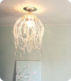 a chandelier hanging from the ceiling above a bed in a room with blue walls