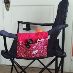 a pink and black folding chair sitting in front of a white door with a red bag on it