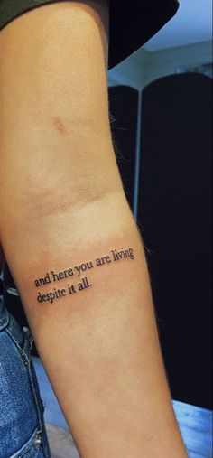 a person with a tattoo on their arm that says and there you are living despite it all