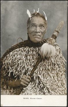 an old photo of a native american man with feathers on his head and arms, holding a stick