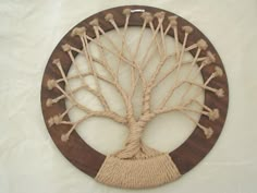 a wooden wall hanging with a tree on it's side and rope wrapped around the base