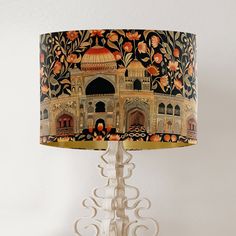 a lamp that is on top of a table with a painting on the lampshade