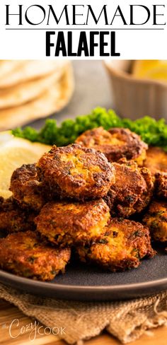 homemade falafel on a black plate with lemon wedges and parsley