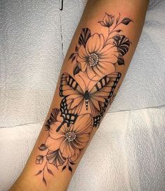 a woman's leg with flowers and butterflies tattoo on the side of her arm