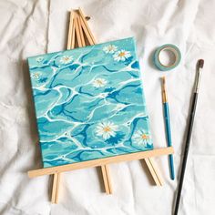 an easel with paint and brushes next to it