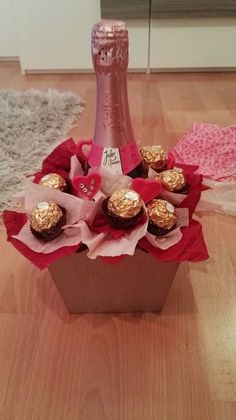 a bottle of champagne sitting on top of a wooden table next to some cupcakes