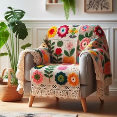 a crocheted blanket on a couch next to a potted plant in a living room