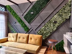 a living room with a couch, coffee table and green plants on the wall behind it