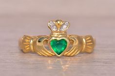 The Balbriggan: Irish Made Designer Signed Green Agate and Natural Diamond Claddagh Ring. Straight from the heart of Ireland, this Claddagh ring showcases a central bezel-set heart crafted from brilliant-cut green agate (dyed chalcedony), beautifully nestled within the iconic Claddagh motif. Adorning the crown are two round-cut natural diamonds, adding a touch of radiance and sophistication. Meticulously crafted in 14 karat yellow gold, the ring is currently sized at 6, with the option for resizing to any finger size available for an additional charge upon request. Handmade in Ireland, this ring bears authentic Irish hallmarks and is proudly signed by its designer, Sol D'or Solvar, reflecting the rich heritage and exquisite craftsmanship of Irish jewelry artistry. The Claddagh ring is a tr Diamond Claddagh Ring, Gold Claddagh Ring, Irish Symbols, Irish Ring Claddagh, Irish Rings, Ring Bear, Straight From The Heart, Claddagh Ring, Claddagh Rings