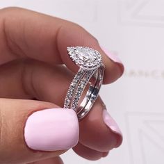 a woman's hand holding a pink manicured nail with a diamond ring on it