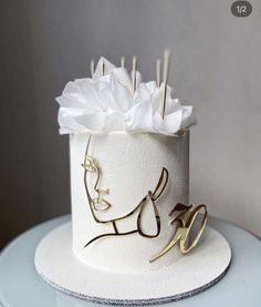 a white cake with gold decoration on top and scissors sticking out of the icing