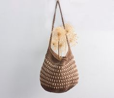 a crocheted bag hanging on a wall with dandelions in the center