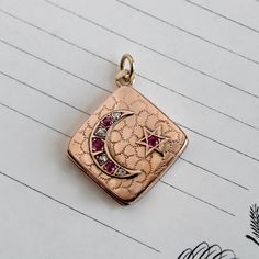 "A wonderful antique locket circa 1895 crafted in 10k rose gold featuring a crescent moon and star on the front cover, set with brightly sparkling old mine-cut diamonds and natural rubies. An engraved shagreen pattern provides a backround for the celestial motif as well as textural interest on the back. Measuring approximately 1\" square the locket opens to reveal space inside for two photos, retaining the original photo holders, and closes securely. The crescent moon, generally interpreted to m Victorian Crescent Jewelry As Gift, Victorian Crescent Jewelry Gift, Victorian Crescent Jewelry For Gifts, Antique Rose Gold Jewelry With Charms, Ruby Locket, Orange Blossom Wedding, Star Locket, Female Strength, Feminine Symbols