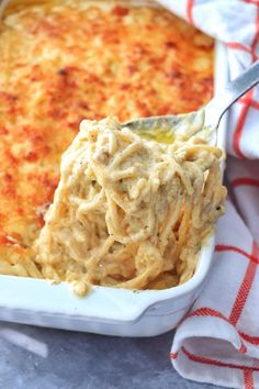 a spoon full of macaroni and cheese in a white casserole dish