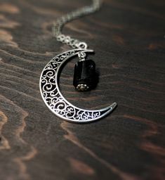 This beautiful crescent moon necklace will inspire all your moonlit nights. This made to order necklace features silver toned metals and a black tourmaline gemstone. product details Silver tone metals Choose your chain length Black tourmaline gemstone; Each piece is unique. The stone varies but is roughly 1/4 inch long or smaller. Each stone is natural and unique. Metaphysical properties of black tourmaline: One of the only stones that heals and protects on all levels, physical, mental, spiritua Gothic Adjustable Necklace With Moon Charm, Spiritual Crescent Moon Phase Crystal Necklace, Bohemian Crescent Crystal Necklace With Moon Charm, Spiritual Crescent Crystal Necklace With Moon Charm, Spiritual Crescent Wire Wrapped Necklaces, Gothic Style Moon Charm Necklace Gift, Gothic Moon Charm Necklace As Gift, Gothic Moon Charm Necklace For Gift, Gothic Necklace With Moon Charm For Gifts