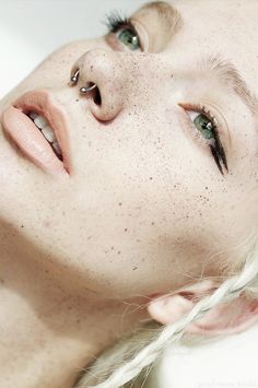 a woman with freckled hair and piercings on her face is looking at the camera