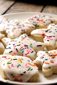 a plate full of white frosted donuts with sprinkles