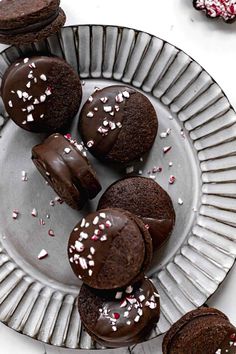 chocolate cookies with white sprinkles on a metal plate next to candy canes