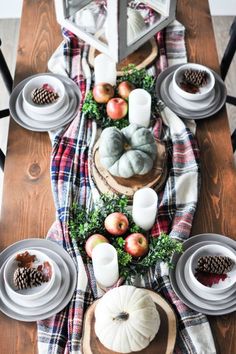 a wooden table topped with plates and bowls filled with food next to pine cone cones