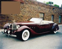 an antique car parked in front of a brick building