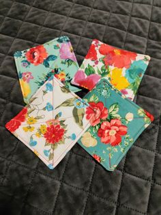 four napkins on a quilted surface with flowers in the middle and one folded