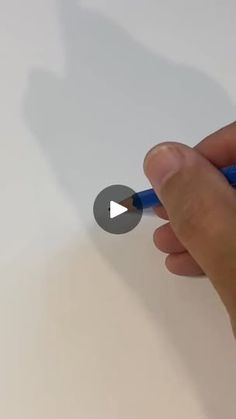 a hand holding a blue marker and writing on a white paper with the tip of a pencil in it