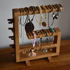 a wooden rack with several necklaces hanging from it's sides on a table