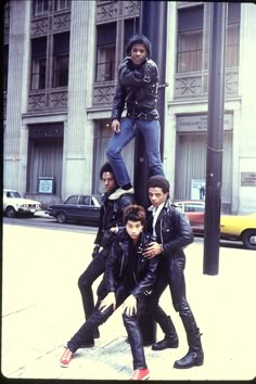 group of young men standing on top of a street light pole in front of a building