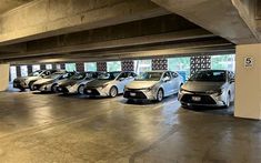 several cars parked in a parking garage with no doors on the side and one is white